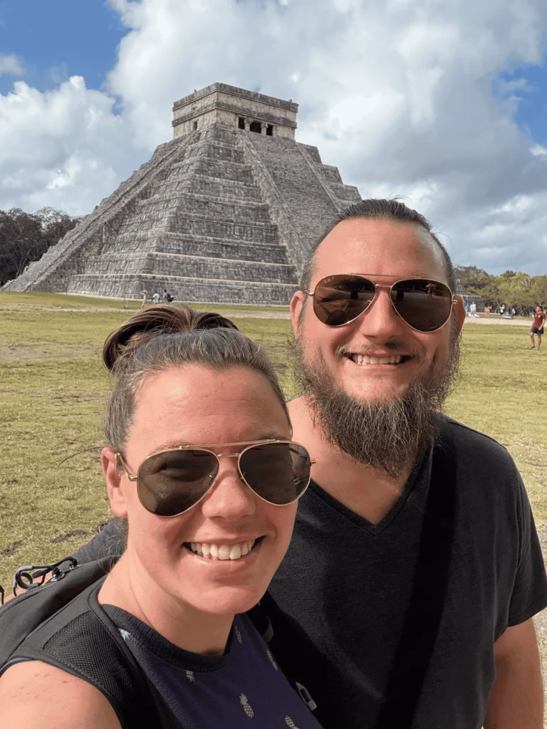 a man and woman taking a selfie in front of a pyramid